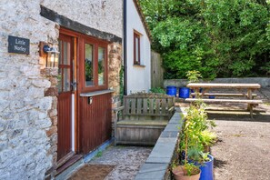 A stone building with a wooden door and a bench outside. - Stunning Bamburgh Coast Apartment (Okehampton)