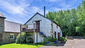 A stone building with a balcony, a chimney, and a paved driveway. - Stunning Bamburgh Coast Apartment (Okehampton)