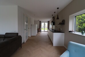 A modern kitchen with a central island, a dining area with a chair, and a sofa. - Private Bungalow With Jetty for 6 (Makkum)
