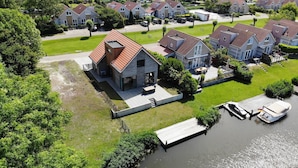 A residential area with houses, a dock, and a small boat. - Private Bungalow With Jetty for 6 (Makkum)