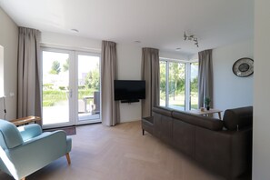 A modern living room with a sofa, a TV, and large windows. - Private Bungalow With Jetty for 6 (Makkum)