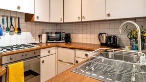 A kitchen with white cabinets, a microwave, a toaster, and a sink with a dish rack. - Peaceful Dorset Cottage for 4 (Bath)