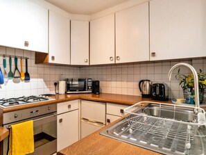 Eine Küche mit weißen Schränken, einer Mikrowelle, einem Toaster und einer Spüle mit Geschirrgestell.