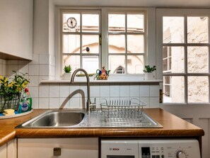 Eine Küche mit Geschirrspüler von Bosch, einem Spülbecken und einem Fenster mit Blick auf ein Gebäude.