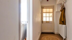 A hallway with a white door, a radiator, and a brown rug. - Peaceful Dorset Cottage for 4 (Bath)