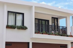 Un bâtiment moderne à deux étages, doté d’un balcon, de grandes fenêtres et d’une porte de garage.