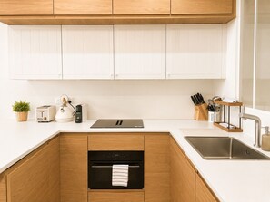 A modern kitchen with white cabinetry, a built-in oven, a stainless steel sink, and a countertop with a toaster, kettle, and coffee maker. - Appartement au Panier • Clim • 4 pers (Marseille)