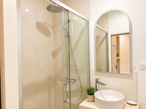 A modern bathroom with a glass-enclosed shower, a round sink, and a mirror with an arch. - Appartement au Panier • Clim • 4 pers (Marseille)