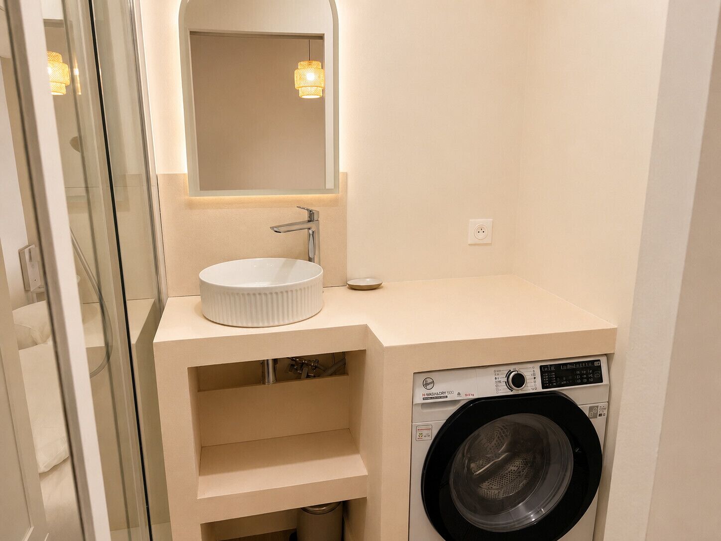 A compact bathroom with a sink, mirror, and washing machine.