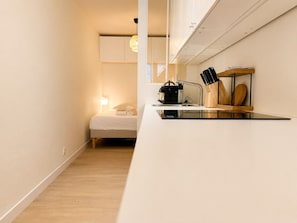A compact hotel room with a kitchenette, a bed, and a small bathroom. - Bail mobilité - Bel appart 1 ch Panier avec clim (Marseille)