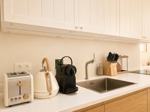 Eine Küche mit Toaster, Wasserkocher, Kaffeemaschine, Spüle und einem Messerblock.