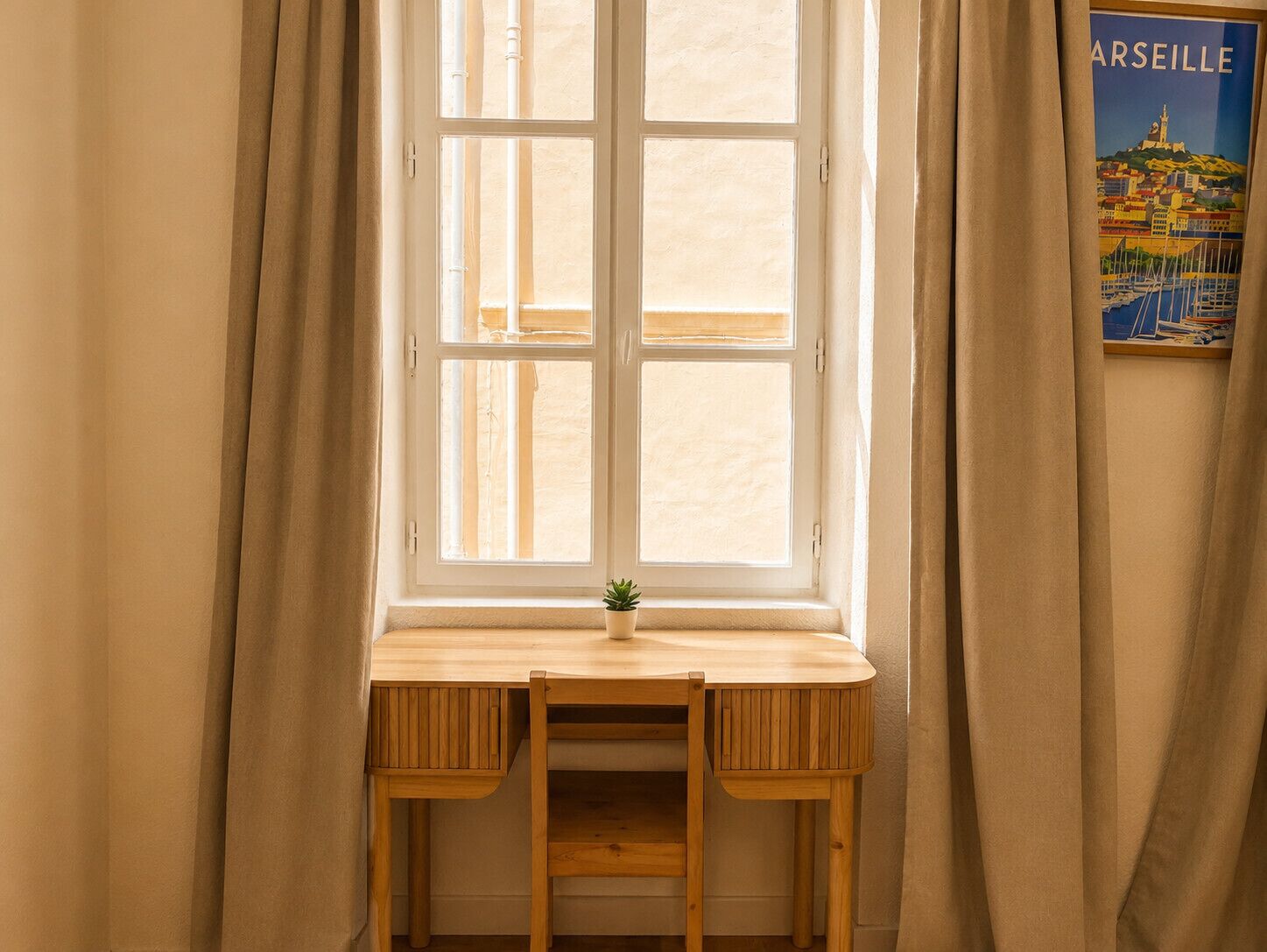 A room with a window, a wooden desk, and a small potted plant.