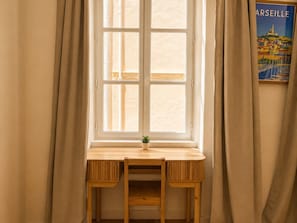 A room with a window, a wooden desk, and a small potted plant. - Bail mobilité - Bel appart 1 ch Panier avec clim (Marseille)