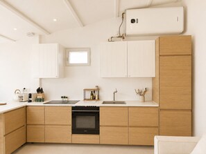 Eine moderne Küche mit Holzschränken, einem eingebauten Backofen und einem Fenster über der Spüle.