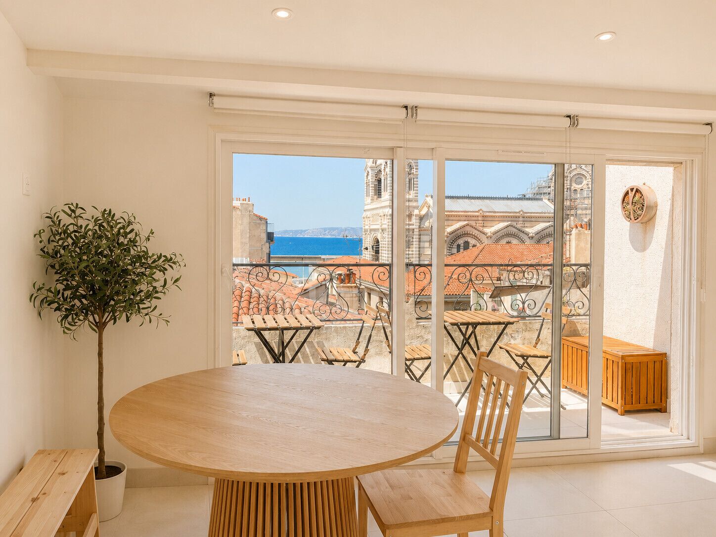 Un balcon avec une table et des chaises, un pot de fleurs et une vue sur un bâtiment historique et la mer.