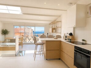 A modern kitchen with a large island, wooden cabinets, and a view of the sea. - Grand T4 vue Major • Panier • Clim • 6 pers (Marseille)