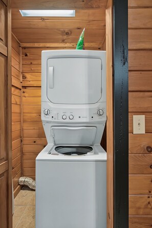 A white washing machine in a wooden cabin with a skylight above. - Cozy Couples Cabin | Fireplace + Hot Tub (Sevierville)