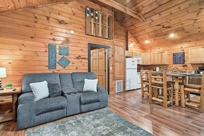 A cozy cabin interior with a sofa, dining table, and kitchen area. - Cozy Couples Cabin | Fireplace + Hot Tub (Sevierville)