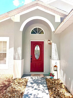 A house with a red door, a welcome mat, and a lantern. - 4BR Family Retreat/ Private Pool/ Kids' Chill Room/ Preserve View (Clermont)