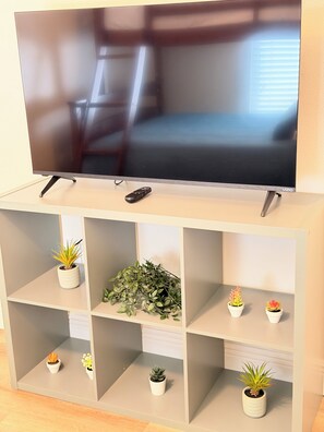 Ein Flachbildfernseher an der Wand, darunter eine Ablage mit einer Fernbedienung.