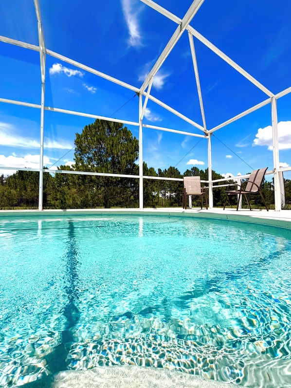 A clear blue pool with a white structure overhead, surrounded by trees and a clear sky. - 4BR Family Retreat/ Private Pool/ Kids' Chill Room/ Preserve View (Clermont)