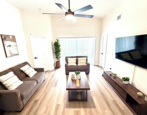A living room with a ceiling fan, a television, a sofa, a coffee table, and a potted plant. - 4BR Family Retreat/ Private Pool/ Kids' Chill Room/ Preserve View (Clermont)
