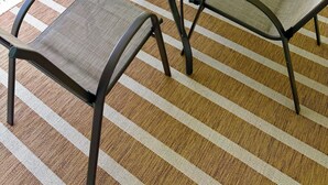 Uma mesa de vidro redonda com quatro cadeiras, um vaso de planta e vista para uma piscina.