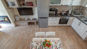 Een moderne keuken met een ingebouwde televisie, een koelkast en een eethoek met twee stoelen.
