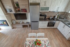 Eine moderne Küche mit integriertem Fernseher, einem Kühlschrank und einem Essbereich mit zwei Stühlen.
