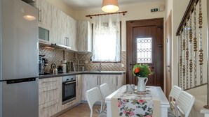 Een moderne keuken met een eethoek, houten vloer en een hangende lamp.