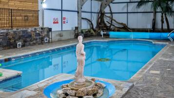 Una piscina interior con una estatua en el centro, rodeada de rocas.