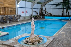 Una piscina interior con una estatua en el centro, rodeada de rocas.