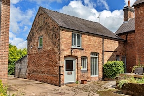 A brick farmhouse with a white door, two windows with shutters, and a chimney. - Scenic Snowdonia Coastal Cabin (Ashbourne)