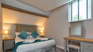 A bedroom with a bed, bedside tables, a desk, a mirror, and a window with blinds. - Scenic Snowdonia Coastal Cabin (Ashbourne)