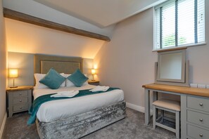 A bedroom with a bed, bedside tables, a desk, a mirror, and a window with blinds. - Scenic Snowdonia Coastal Cabin (Ashbourne)