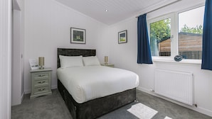 Een slaapkamer met een bed, nachtkastjes, een raam met gordijnen en een radiator.