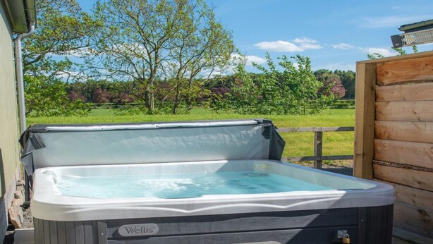 Een bubbelbad met een houten terras en een houten omheining op de achtergrond.