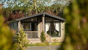 Een chalet met een veranda, grote ramen en een klein terras.