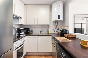 A modern kitchen with white cabinets, a built-in oven, a microwave, a sink, and a water heater. - Apartment with Terrace and Rooftop in Casares Costa (Casares)