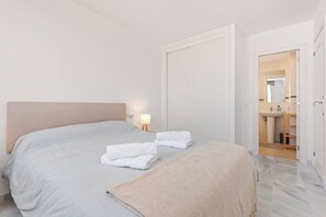 A hotel room with a bed, two towels, a bedside lamp, and a view of the bathroom. - Apartment with Terrace and Rooftop in Casares Costa (Casares)