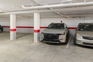 A parking garage with two cars parked under white pillars with red stripes. - Apartment with Terrace and Rooftop in Casares Costa (Casares)