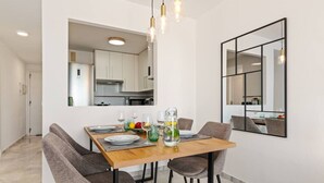 Et moderne spiseområde med et træbord dækket til fire personer, omgivet af grå polstrede stole.