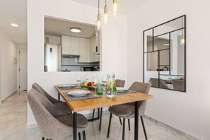 A modern dining area with a wooden table set for four, surrounded by grey upholstered chairs. - Apartment with Terrace and Rooftop in Casares Costa (Casares)