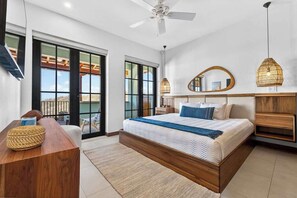 A bedroom with a bed, a desk, a chair, a ceiling fan, and a large window. - Las Catalinas Escape, Ocean View & Plunge Pool (Las Catalinas)