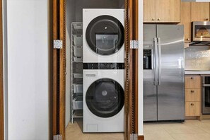 A kitchen with a stainless steel refrigerator, a washing machine, and wooden cabinets. - Las Catalinas Escape, Ocean View & Plunge Pool (Las Catalinas)
