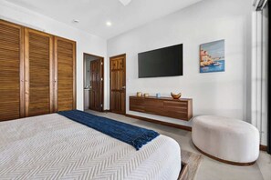 A bedroom with a large bed, wooden wardrobes, a television, and a painting on the wall. - Las Catalinas Escape, Ocean View & Plunge Pool (Las Catalinas)