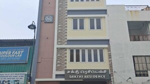 Un edificio de varios pisos con un letrero que dice 'SAKTHI RESIDENCY' y un 'SUPER FAST COLOUR LAB' a su lado.