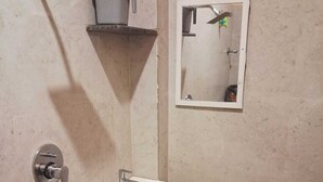 Un baño con ducha, lavamanos y espejo.