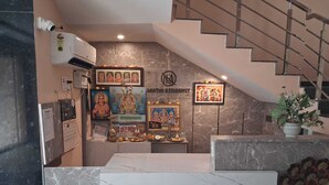 Un área de recepción con mostrador de mármol, una escalera y decoraciones religiosas.