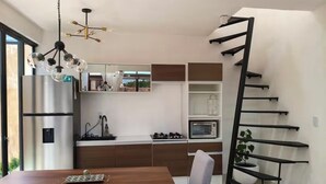 Eine moderne Küche mit eingebautem Backofen, einem Edelstahl-Kühlschrank und einem Essbereich mit Holztisch und Stühlen.